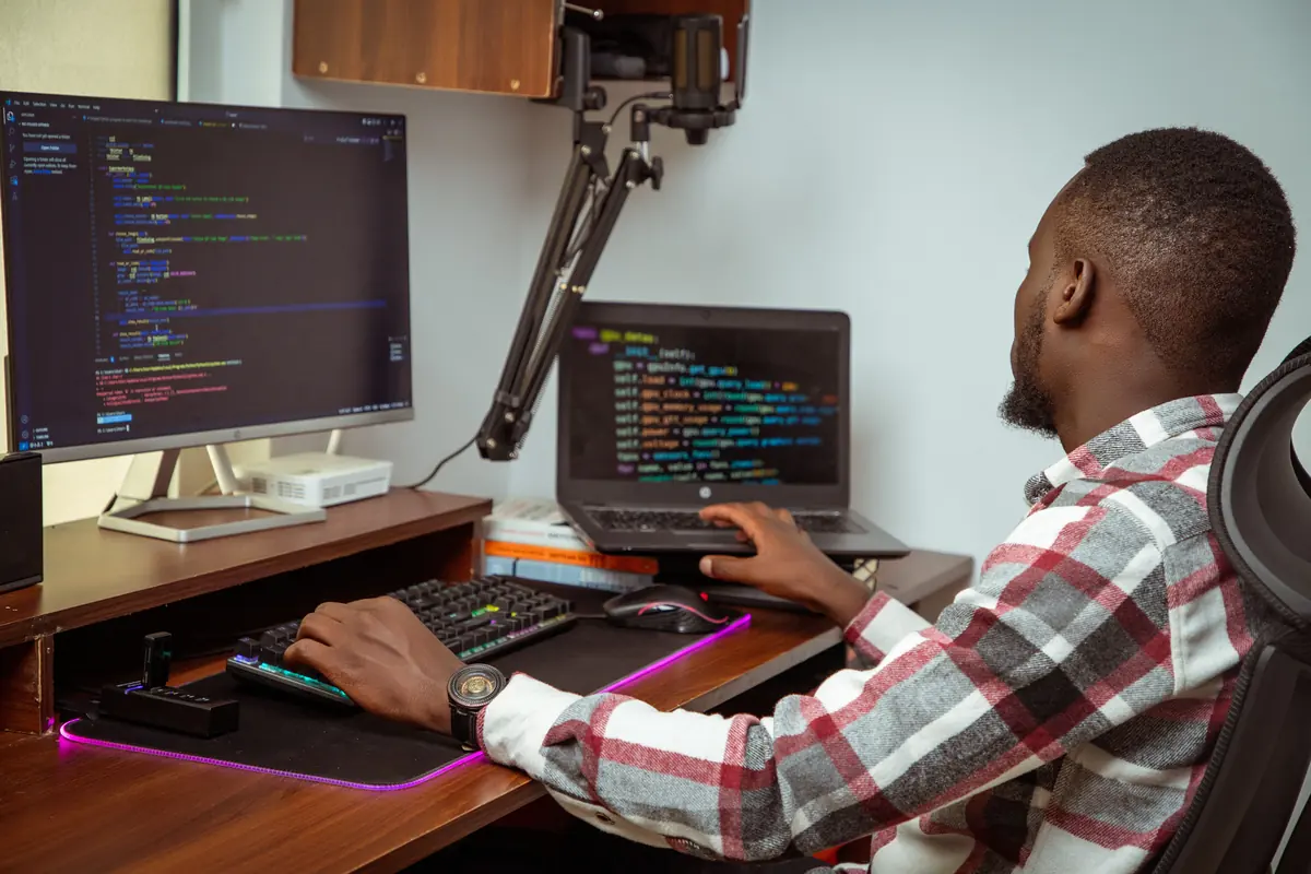 A developer at a desk with code on two screens